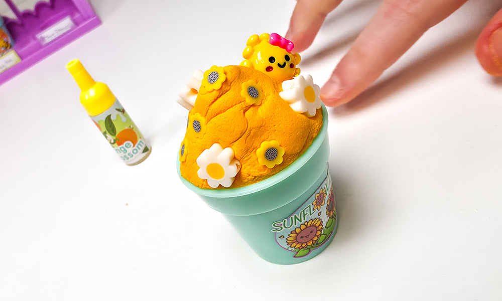 Child decorating sunflower orange butter slime in a So Slime Flower Mini Garden flowerpot with c