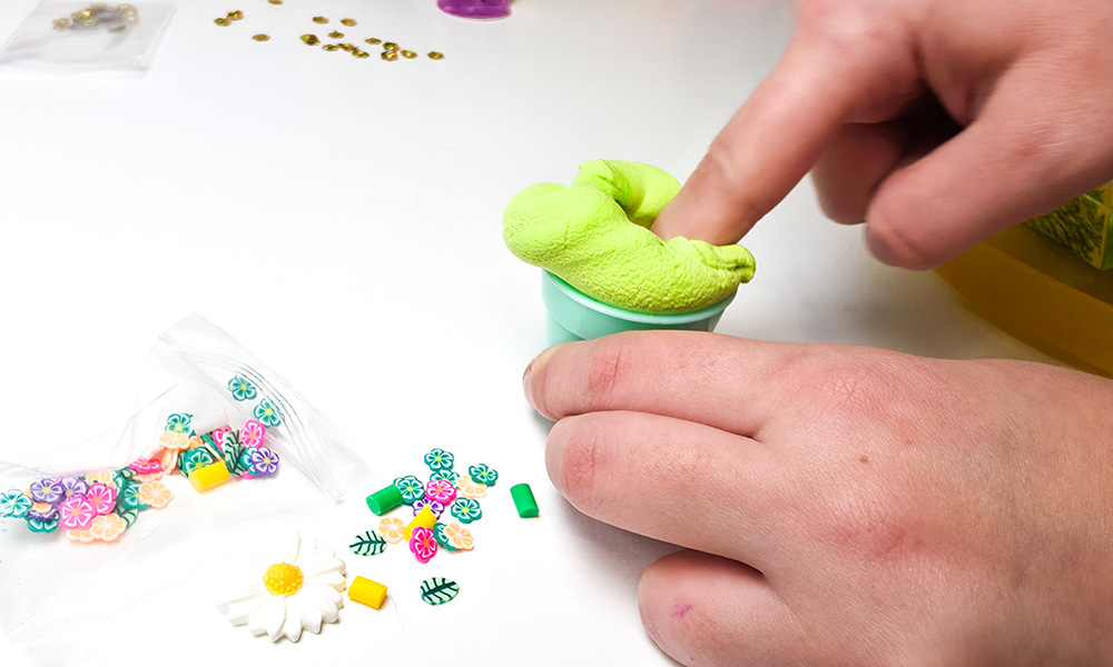 Child pressing light green spring scented butter slime into a So Slime Flower Mini Garden flower