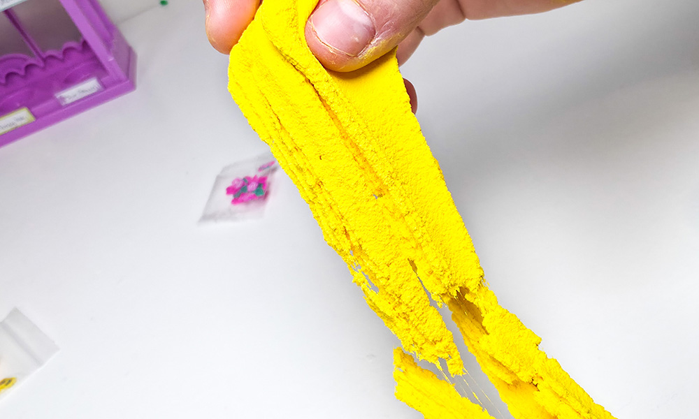 Child stretching bright yellow butter slime made with the So Slime Flower Mini Garden craft kit