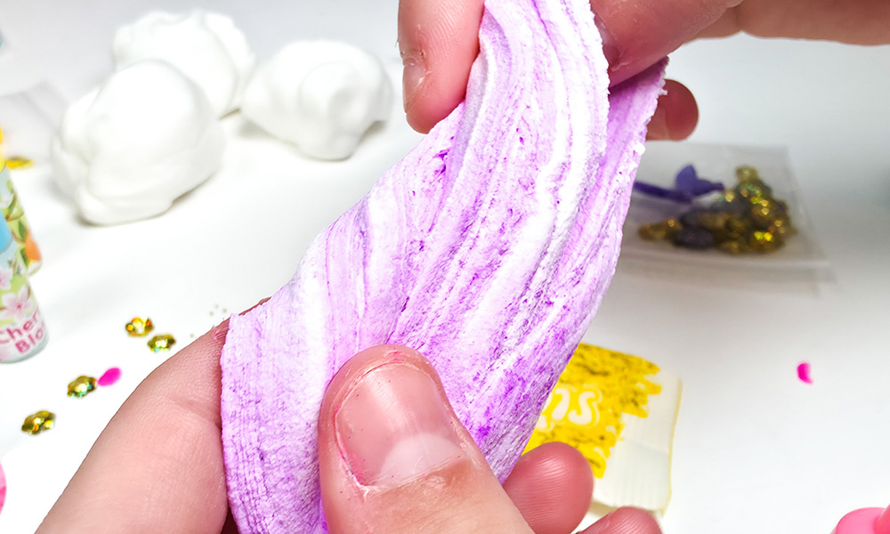 Mixing purple powder dye into white butter slime
